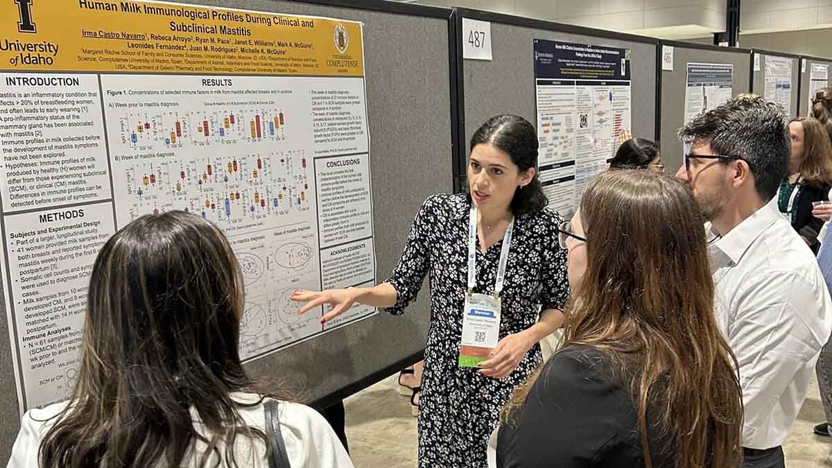 A woman at a conference talkin about her research to group.