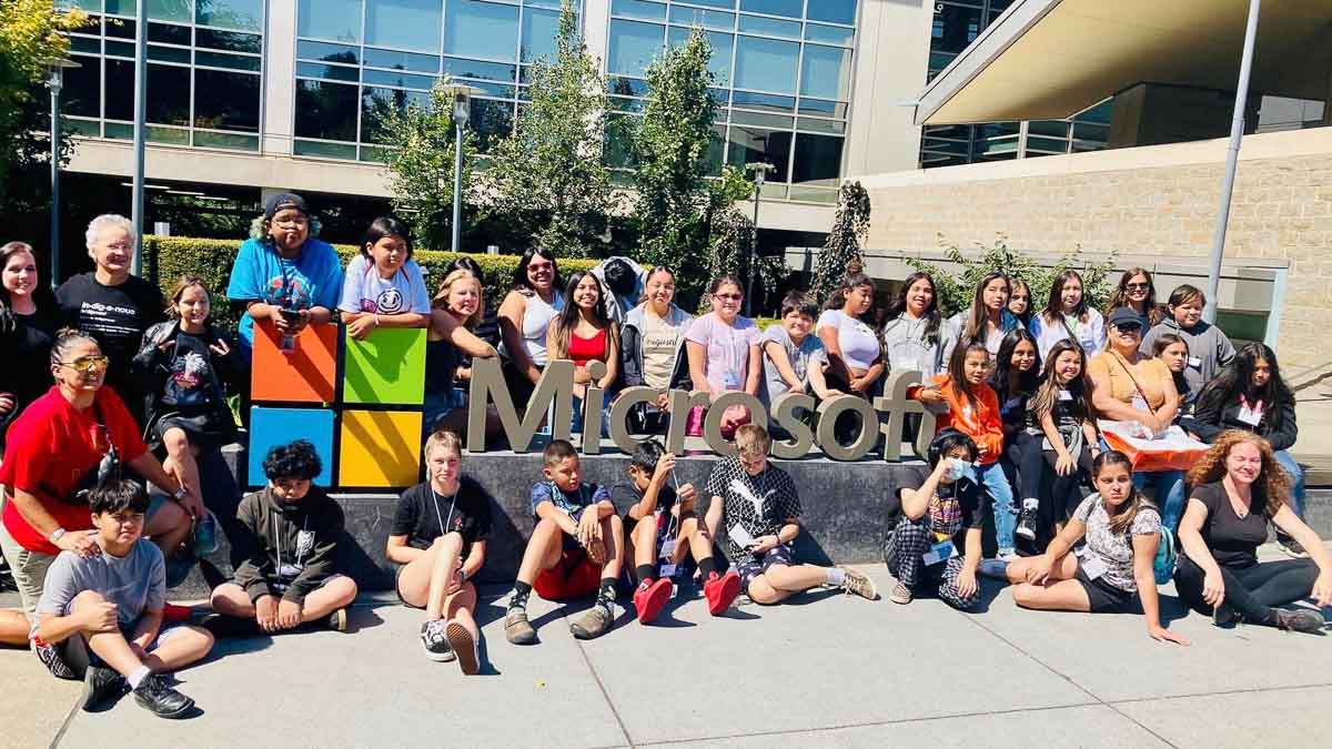 Youth pose in from of Microsoft sign.